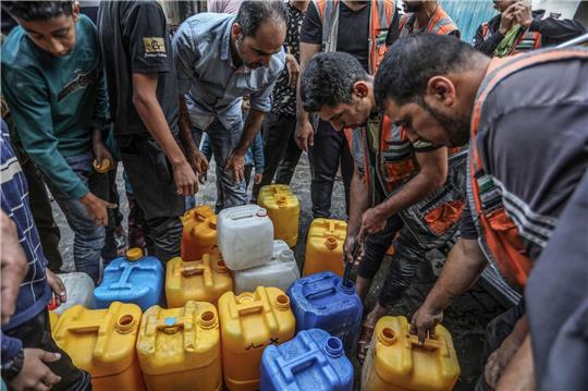 Palästinenser stehen in Rafah Schlange, um an Wasser zu gelangen.