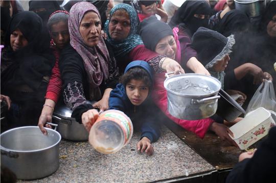Palästinenser stehen während der israelischen Luft- und Bodenoffensive für die kostenlose Verteilung von Lebensmitteln an.