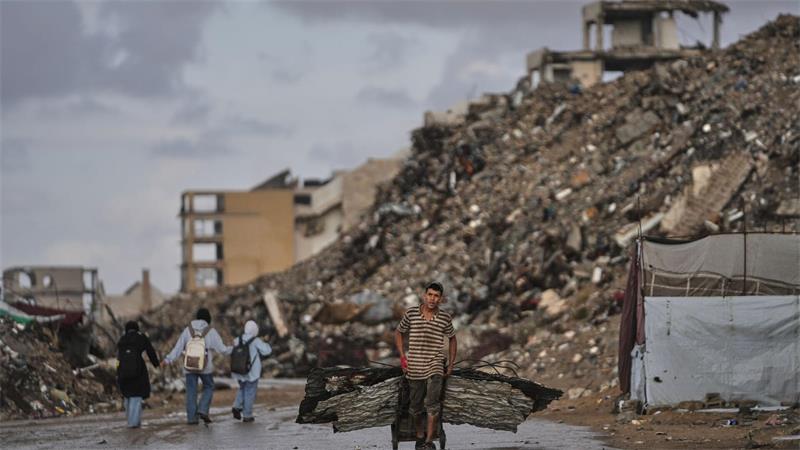 Palästinenser trägt Bleche durch Kriegsschutt in Gaza