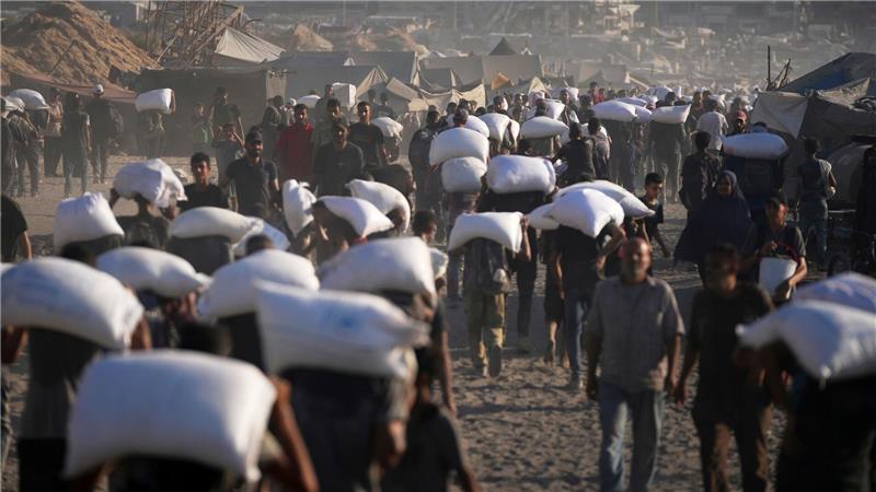 Palästinenser tragen Mehlsäcke, die von einem humanitären Hilfskonvoi auf dem Weg vom nördlichen Gazastreifen nach Gaza abgeladen wurden.