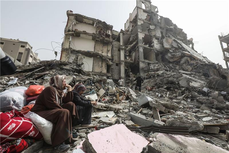 Hamas stimmt einer Waffenruhe im Gazastreifen zu Palästinenserinnen sitzen auf Trümmern im Flüchtlingslager Nuseirat im Gazastreifen nach dem Abzug der israelischen Streitkräfte (IDF).