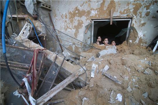 Palästinensische Kinder schauen in Rafah im Süden des Gazastreifens aus einem Fenster, das bei israelischen Luftangriffen zerstört wurde.
