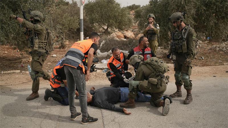 Palästinensische Sanitäter und ein israelischer Soldat kümmern sich um einen palästinensischen Mann, der von israelischen Soldaten angeschossen wurde.
