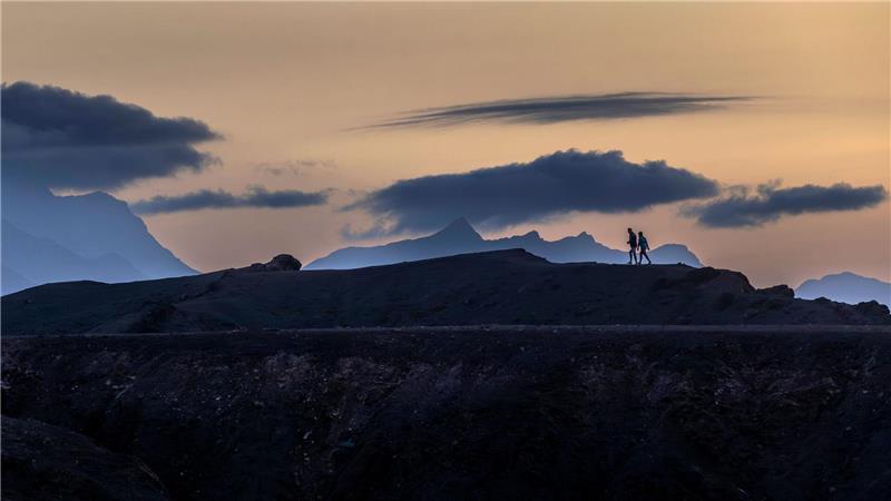 Bilder des Tages Panodrama: Menschen gehen auf der Insel Fuerteventura unter dramatisch wirkenden Wolkenformationen.