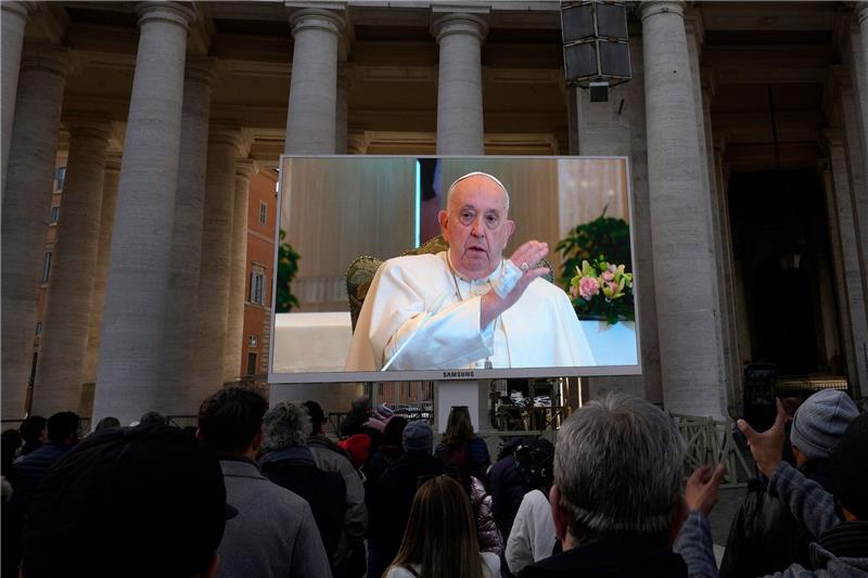 Papst Franziskus ist auf einem Monitor zu sehen, um die Gläubigen zu segnen, die sich auf dem Petersplatz versammelt haben.