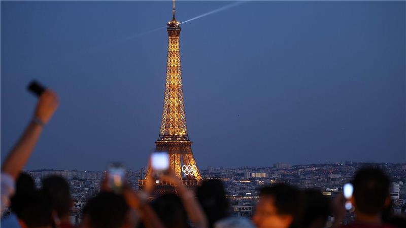 Paris im Sommer 2024 - besonders beliebt: Touristen fotografieren den Eiffelturm mit den Olympischen Ringen von der Terrasse des Triumphbogens. (Archivbild)