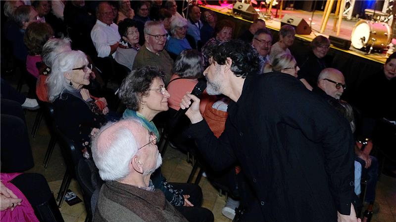 Ein schwarz Gekleideter geht mit Mikrofon ins Publikum und singt eine Frau an.