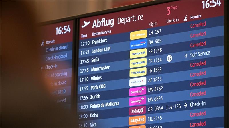 Passagiere blicken auf eine Anzeigetafel am Hauptstadtflughafen BER.
