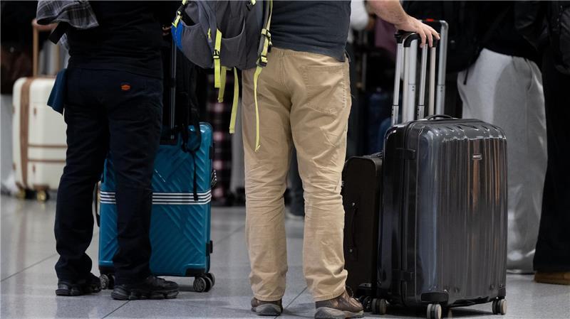 Passagiere stehen am Münchner Flughafen mit ihrem Gepäck an einem Check-in-Schalter.
