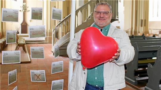 Abschied nach Jahrzehnt: Pastor Dittmann behält den Harz im Herzen Pastor André Dittmann hält einen herzförmigen roten Luftballon in der Hand. Er steht in der Zellerfelder Kirche.