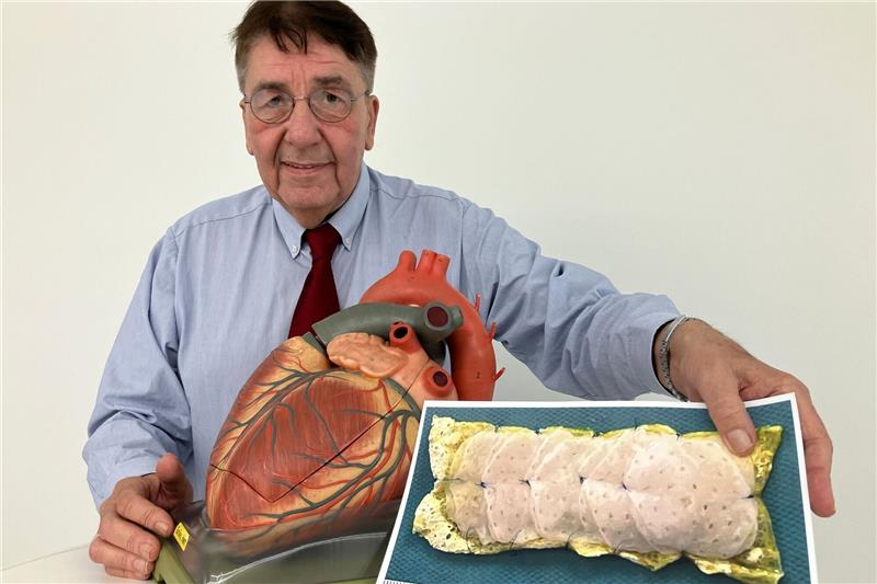 Neue Therapie gegen Herzmuskelschwäche: Patient berichtet Patient Frank Teege steht neben einem Herz-Modell und zeigt ein Bild eines Herzpflasters.
