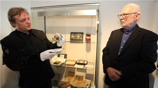 Zwei Männer stehen vor einer Glasvitrine.