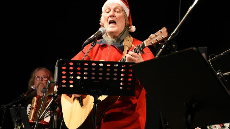 Ein Sänger mit Weihnachtsmütze spielt Gitarre.