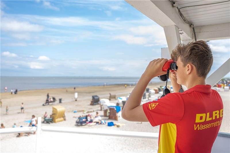 DLRG sucht Rettungsschwimmer für Badesaison Peter von der DLRG-Wasserrettung steht auf einem Turm und beaufsichtigt mit einem Fernglas den Badestrand von Dangast.