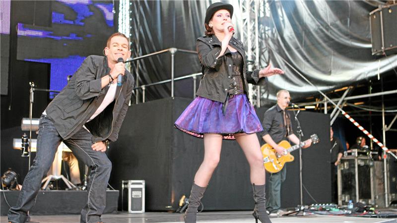 Zwei Sänger und ein Gitarrist auf einer Bühne bei einem Live-Konzert