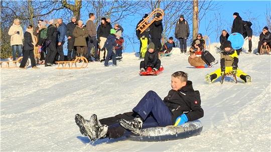 Kinder und Jugendliche rodeln einen Hang hinab.