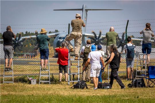 Planespotter stehen an einem Zaun vor dem Fliegerhorst Wunstorf und fotografieren einen Airbus A400M der Luftwaffe.