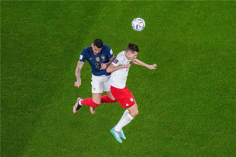 Polens Jakub Kaminski (r) kämpft im WM-Achtelfinale mit Frankreichs Theo Hernandez um den Ball.