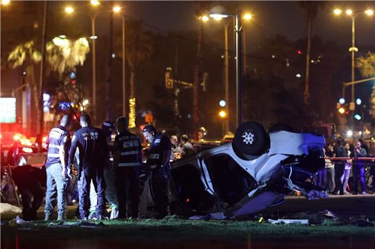 Polizei und der Rettungsdienst stehen nahe des Strands von Tel Aviv neben dem Auto, das sich überschlagen hat.