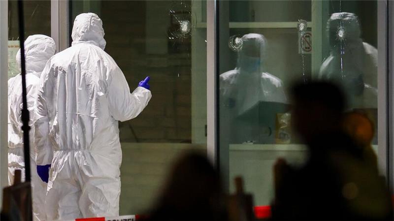 Vorfall in Krefeld: Was wir wissen – und was nicht Polizeibeamte der Spurensicherung in weißen Schutzanzügen untersuchen Löcher in Glasscheiben des Kinos.