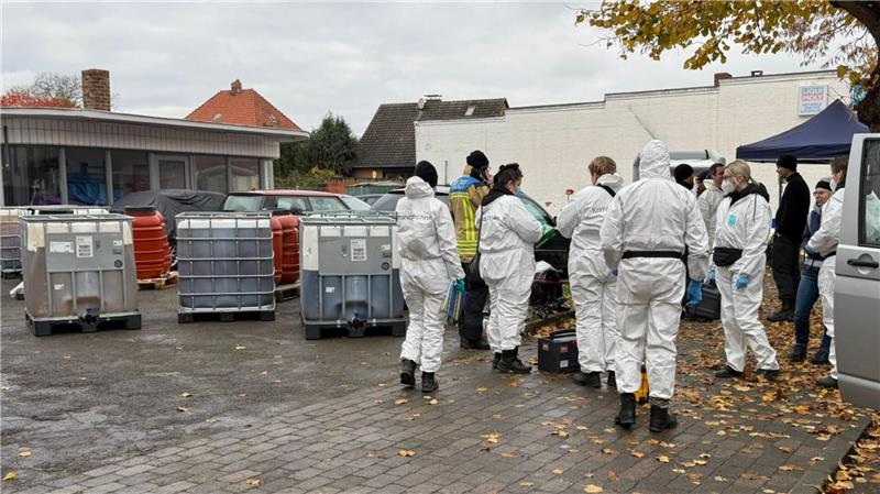 Polizeibeamte in Schutzanzügen in Schöppenstedt. Mehrere große Fässer stehen auf einem Privatgelände.