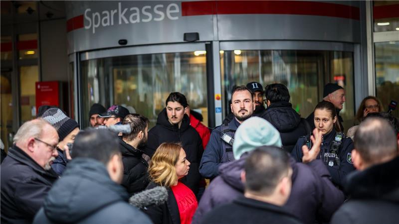 Polizeibeamte sprechen mit möglicherweise betroffenen Kunden der Sparkassenfiliale in Buer.