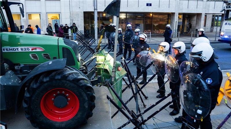 Feuer und Tränengas: Tausende Bauern bei Protest in Brüssel Polizisten bewachen eine Absperrung.