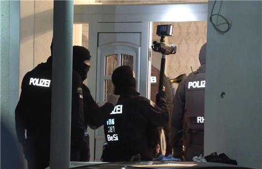 Polizisten dringen im Rahmen einer groß angelegten Razzia in ein Haus ein.