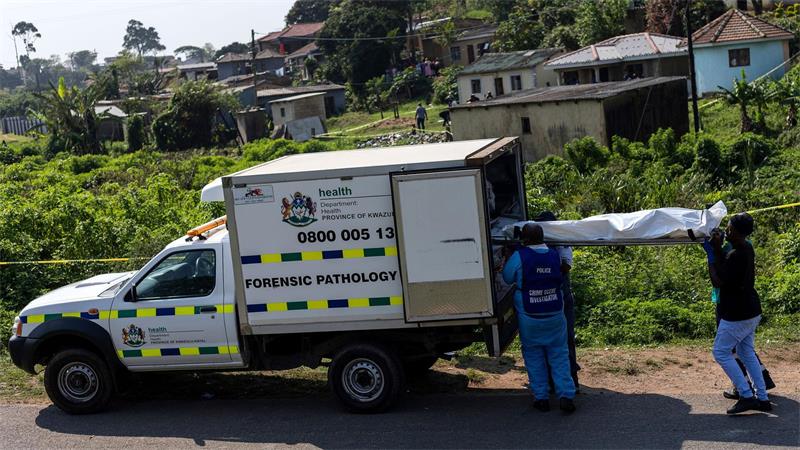 Elf Tote nach Schusswaffenangriff auf Feier in Südafrika Polizisten laden eine Leiche in ein Fahrzeug der Gerichtsmedizin.
