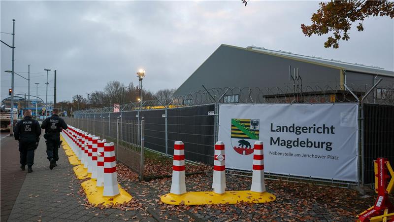 Polizisten laufen vor dem temporären Gerichtsgebäude des Landgerichtes Magdeburg Streife.