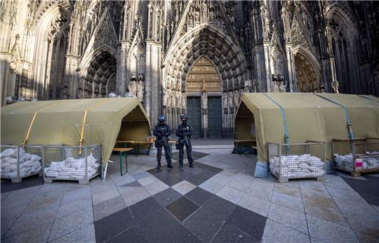 Polizisten mit Maschinenpistolen stehen vor dem Kölner Dom. Nach dem Terroralarm für das Gotteshaus sind drei weitere Verdächtige festgesetzt worden.
