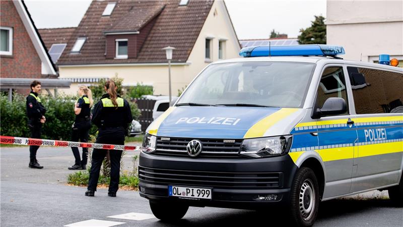 Polizisten sperren den Tatort mit Absperrband und Polizeiautos ab. 
