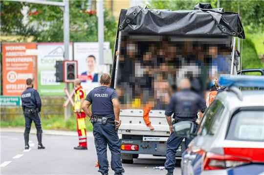 Polizisten stehen bei einer Kontrolle in Österreich an einem Kleintransporter. Die Beamten entdeckten dabei 53 Personen auf der Ladefläche.