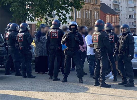 Polizisten stehen bei einer Massenschlägerei n Castrop-Rauxel auf der Straße und schirmen eine Gruppe von Personen ab.