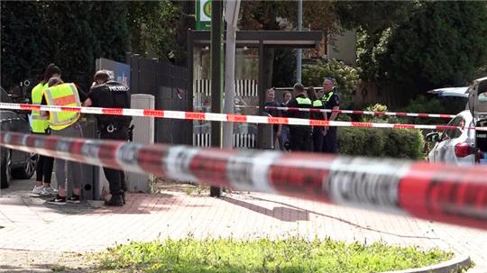 Polizisten stehen hinter Absperrband am Tatort im Bereich der Bahnhofstraße. Bei einer mutmaßlichen Stichwaffen-Attacke ist ein 61-Jähriger gestorben.