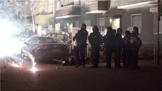 Polizisten stehen in der Silvesternacht 2022 hinter explodierendem Feuerwerk in Berlin.