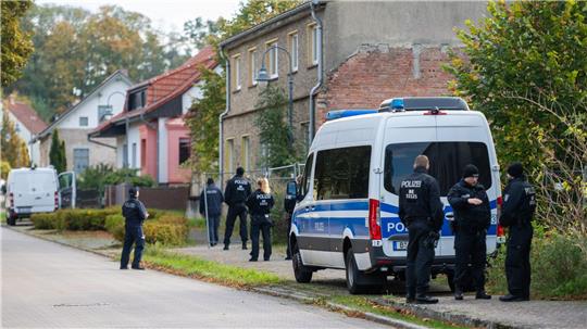 Polizisten stehen vor einem Grundstück in Tauche.