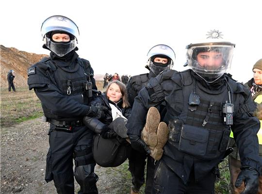 Polizisten tragen die schwedische Klimaaktivistin Greta Thunberg aus einer Gruppe von Demonstranten und Aktivisten heraus vom Rand des Braunkohlentagebaus Garzweiler II weg.