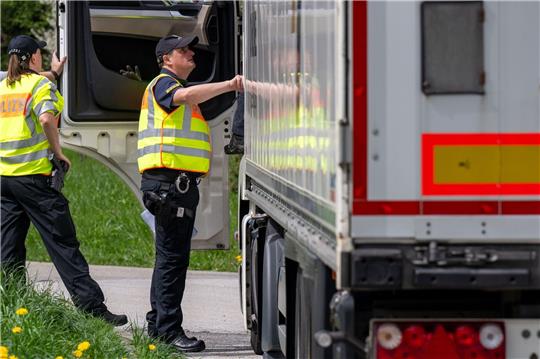 Polizisten überprüfen bei einer Verkehrskontrolle einen Lastwagen.