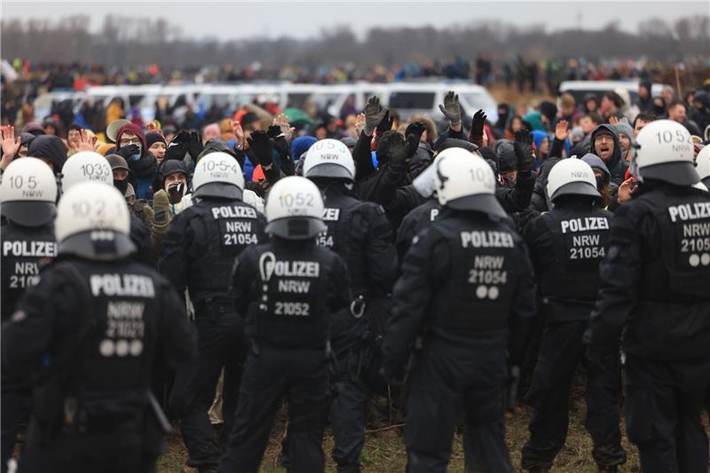 Polizisten und Demonstranten stehen sich bei der Demonstration von Klimaaktivisten am Rande des Braunkohletagebaus bei Lützerath gegenüber.
