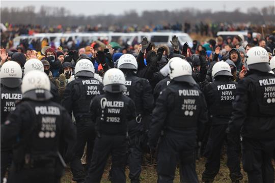 Polizisten und Demonstranten stehen sich bei der Demonstration von Klimaaktivisten am Rande des Braunkohletagebaus bei Lützerath gegenüber.
