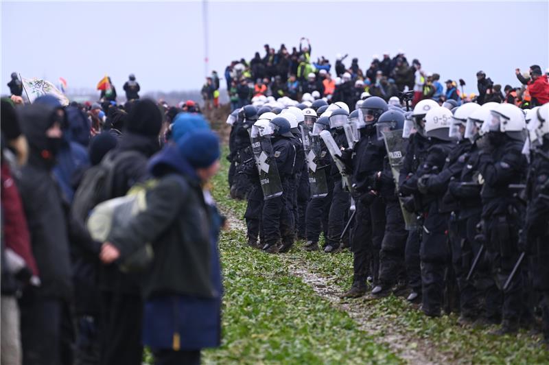 Polizisten und Demonstranten stehen sich bei der Demonstration von Klimaaktivisten am Rande des Braunkohletagebaus bei Lützerath gegenüber. Foto: Henning Kaiser/DPA