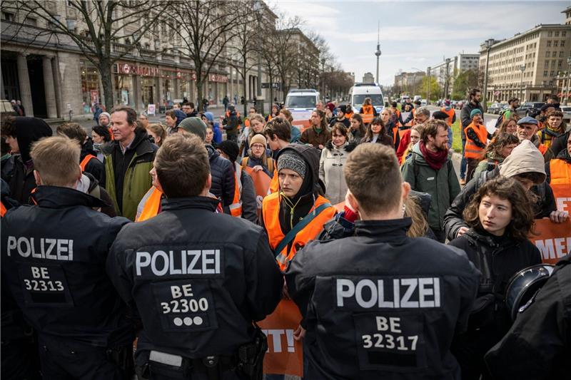 Klimaaktivisten starten Blockaden in Berlin Polizisten und Teilnehmer des Protests stehen sich auf der Karl-Marx-Allee in Berlin gegenüber.