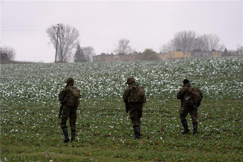 Polnische Soldaten suchen auf einem Acker nach Wrackteilen.