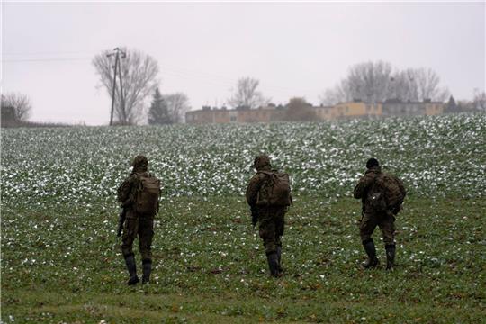 Polnische Soldaten suchen auf einem Acker nach Wrackteilen.
