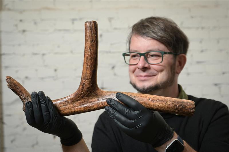 Ein Mann hält ein Geweih in den Händen.