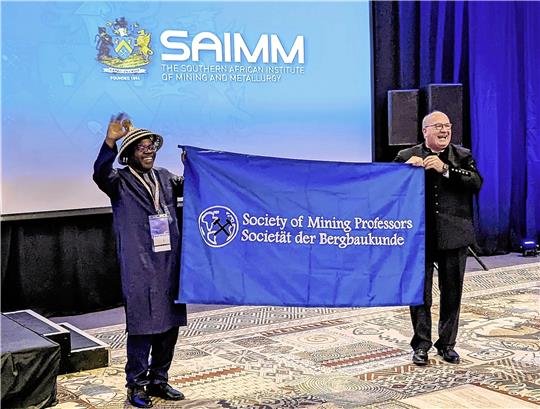 Prof. Oliver Langefeld (rechts) übernimmt als neuer Präsident der „Society of Mining Professors“ die Flagge von seinem Vorgänger Prof. Harmony Musyarira, Head of Departement an der Namibian University of Science and Technology. Foto: TU Clausthal