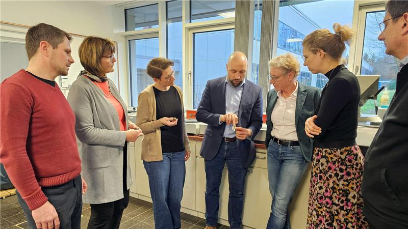 TU Clausthal erhält zehn Millionen Euro für Forschungsprojekte Sechs Personen stehen in einem Halbkreis. Der Mann in der Mitte hält einen Gegenstand in der Hand und erzählt etwas.