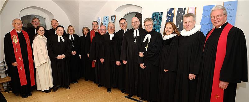 16 kirchliche Amts-und Würdenträger in festlicher Kleidung stehen zum Pressefoto nebeneinander und blicken in die Kamera. 