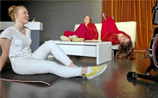Protagonistin Mia Holl wird nach und nach zur Gegnerin der Gesundheitsdiktatur. Hanne Nitväli und Henrike Weiß sitzen auf dem Sofa und spielen gemeinsam die ideale Geliebte. Das ist eine Figur, die Moritz vor seinem Tod erfunden hat. Foto: Knoke